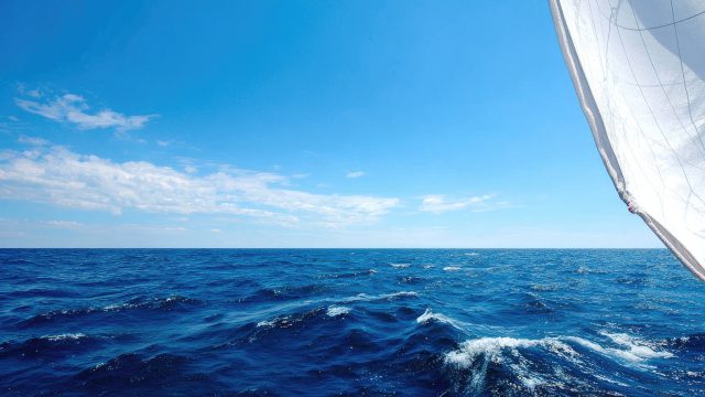 Luxury sailboat helm offers serene views in a marina on a sunny summer day, perfect for adventure and relaxation on the water