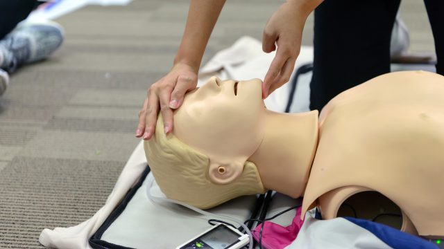 CPR First Aid Training with CPR dummy in the class